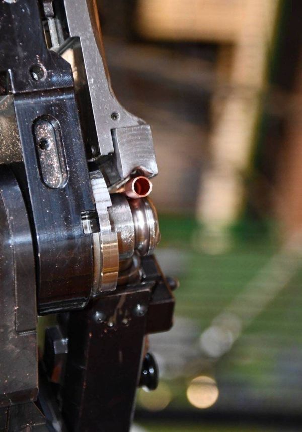 Detail of CNC tube bending machine forming a copper tube end for HVAC components.