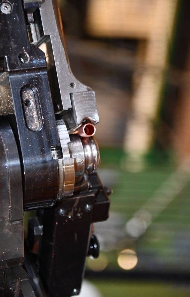 Détail d’une machine de cintrage de tubes CNC formant une extrémité de tube en cuivre pour des composants CVC.